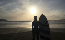 Surfer with surf board in sunset